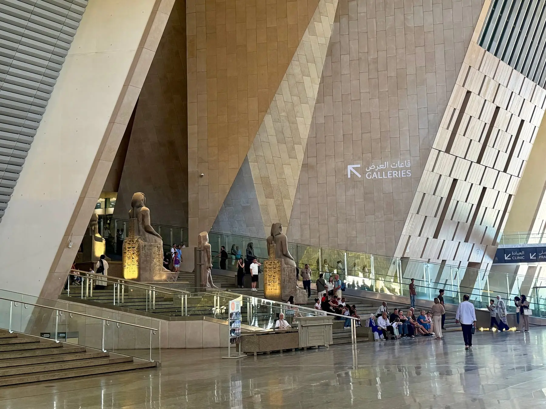 The Grand Hall of the Grand Egyptian Museum with statues and the sign to the galleries