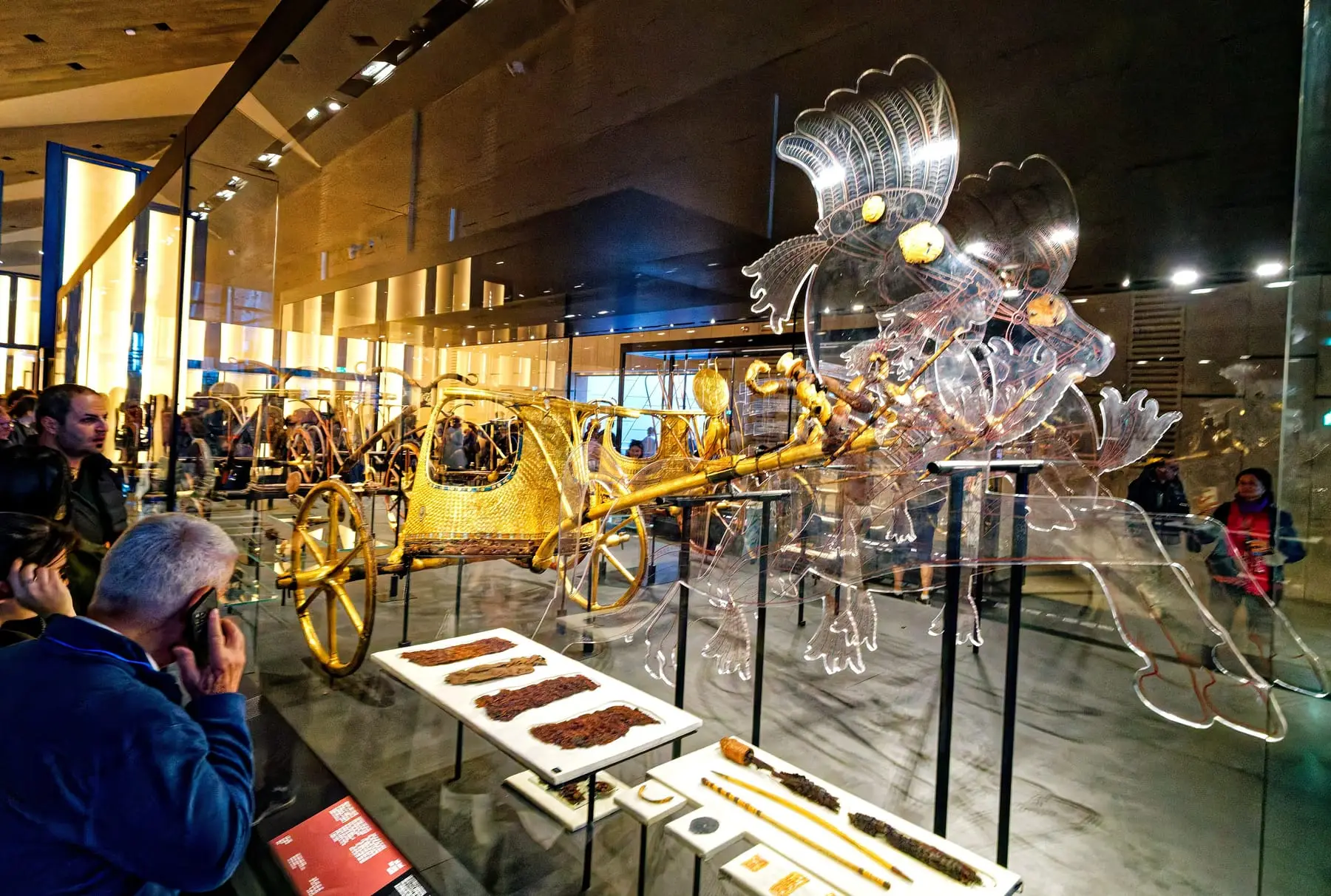 Tutankhamun’s gilded chariots displayed in glass cases at the Grand Egyptian Museum